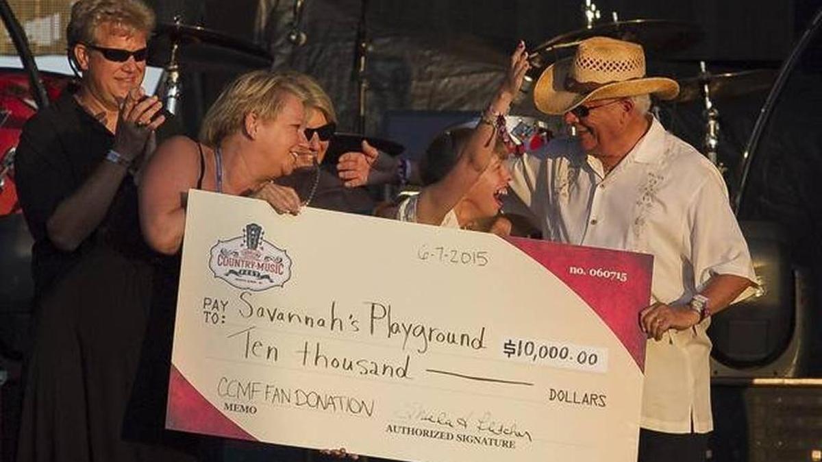 Savannah Thompson receives a check with Mayor John Rhodes for Savannah's Playground from the Carolina Country Music Fest in June 2015.