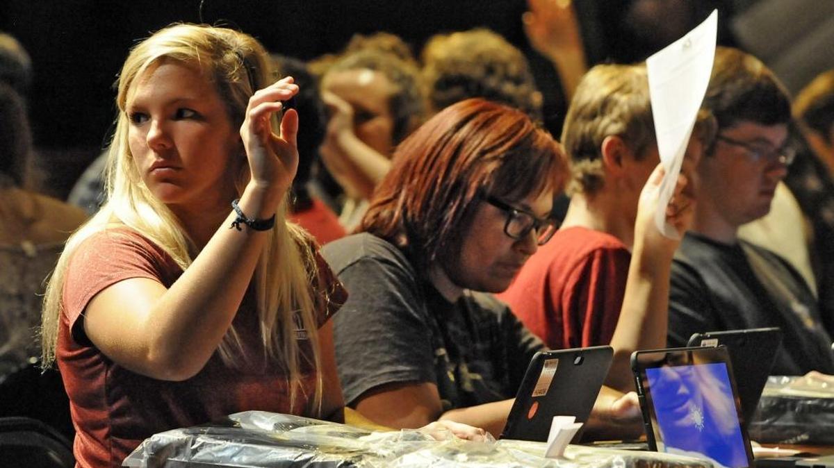 Rayni Newman raises her hand as she and Jenna Nesmith, students at the Academy of the Arts, Science and Technology complete paperwork and log into their Dell Venue tablets last year.