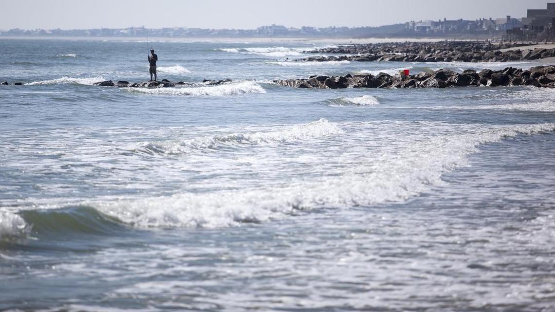 A fisherman stands on a rock groin along the South Carolina coast. Groins are supposed to help protect beaches from erosion, but critics say they don’t work.
