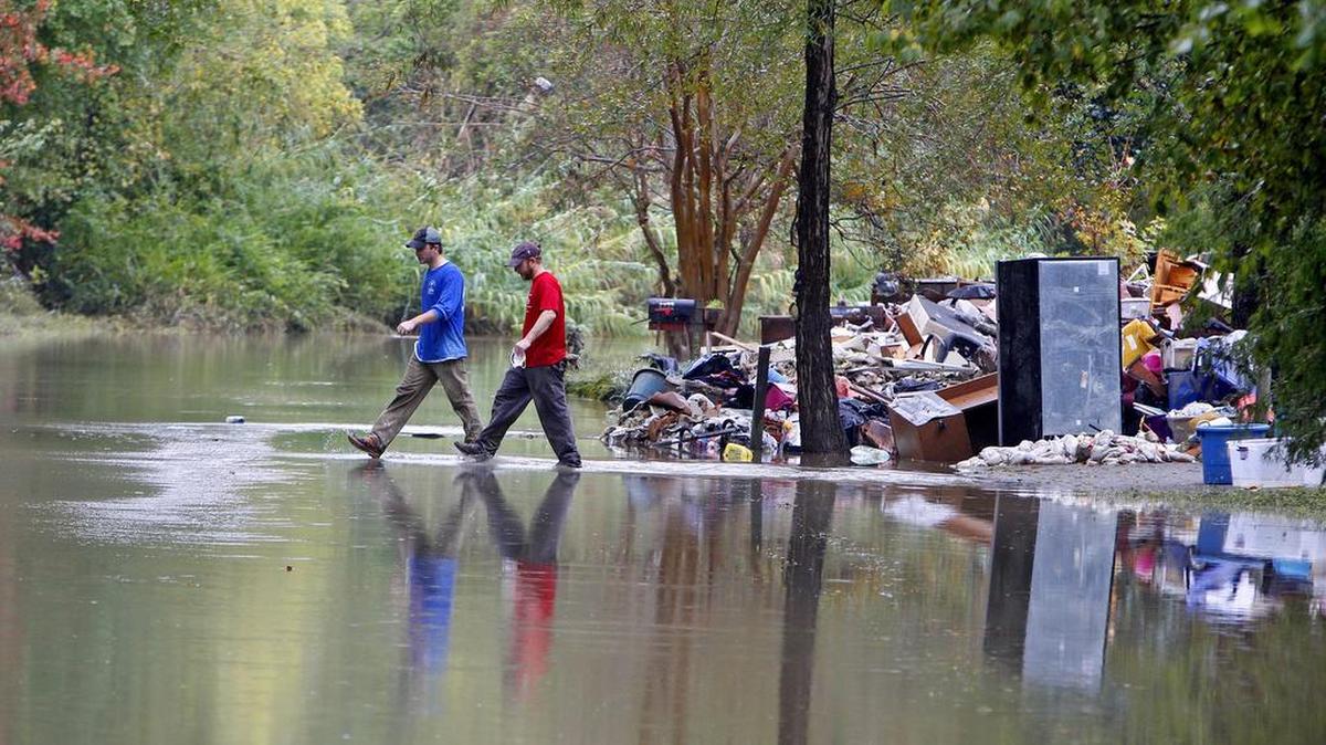 Ricky Spitz and Riley Maxwell walk through flood waters on Timberlane Drive in Columbia in the wake of the October.