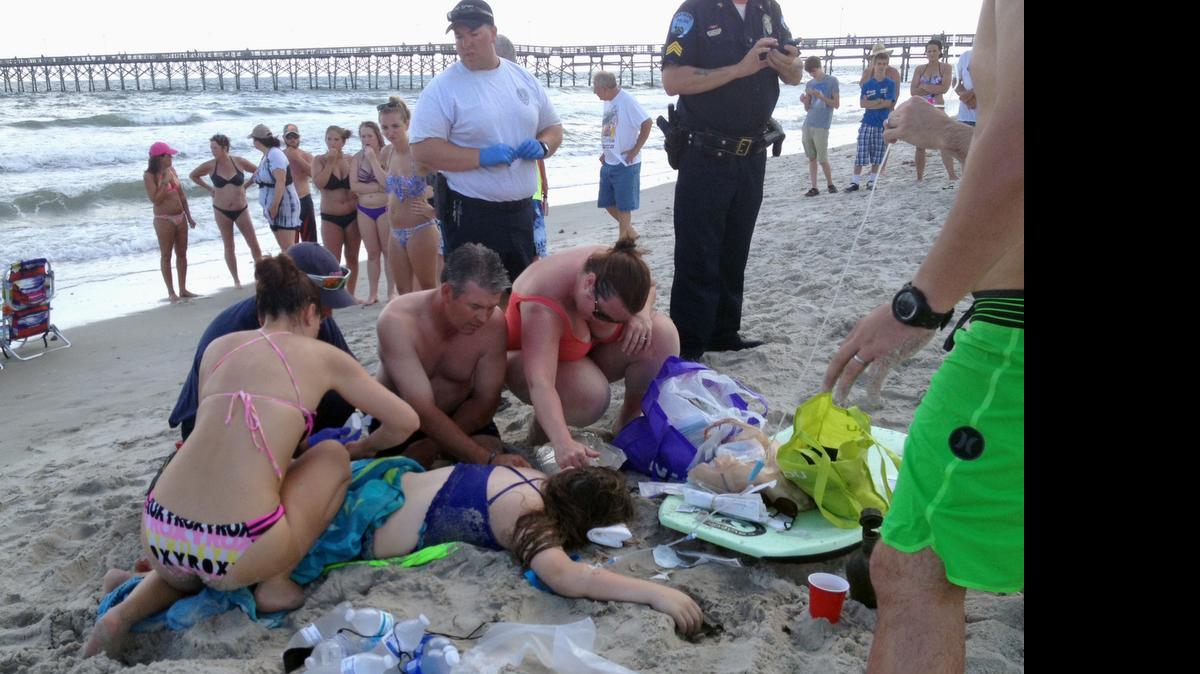 
Emergency responders assist a teenage girl at the scene of a shark attack in Oak Island, N.C., Sunday, June 14, 2015. Mayor Betty Wallace of Oak Island, a seaside town bordered to the south by the Atlantic Ocean, said that hours after the teenage girl suffered severe injuries in a shark attack Sunday a teenage boy was also severely injured. (Steve Bouser/The Pilot, Southern Pines, N.C. via AP) 
