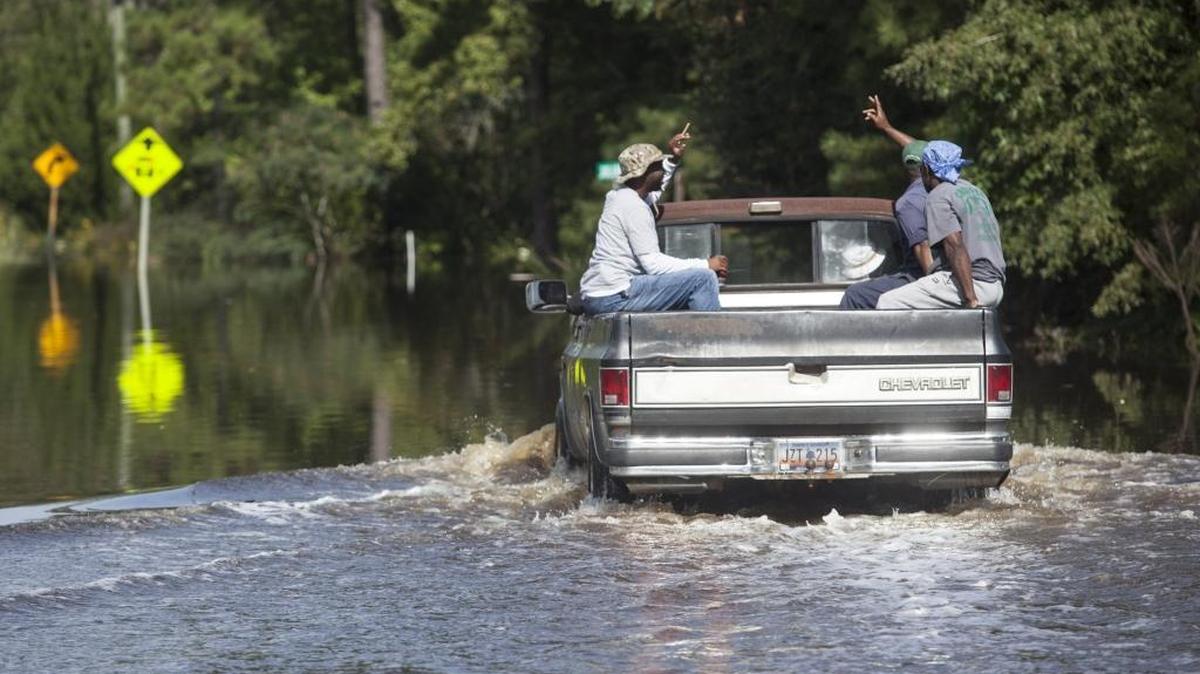 Residents of the Dunbar community near Georgetown wave to neighbors as they help each other evacuate under threat of flooding from the Black River in October.