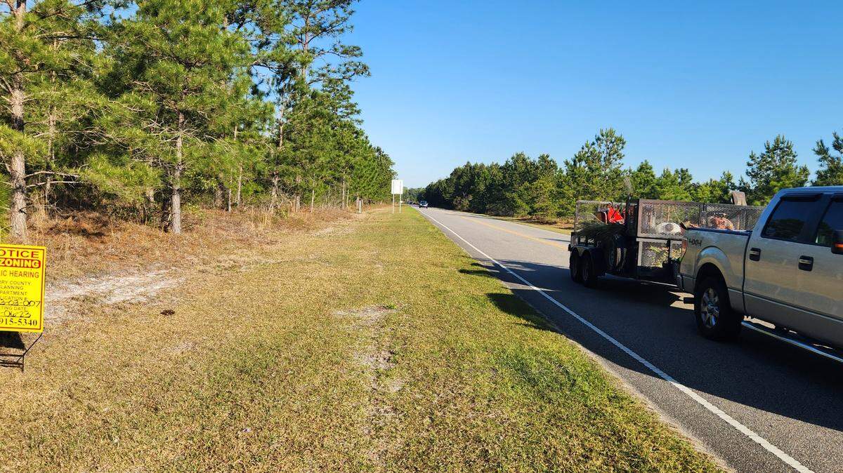 A motorist travels down Postal Way on March 30, 2023. The wooded area could give way to more than 1,000 homes and retail if county leaders approve development plans.