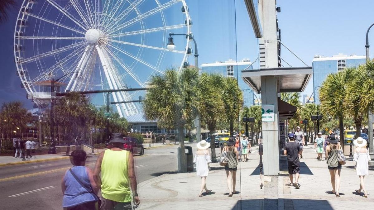 Pedestrians are reflected in a store front window between Ninth Avenue and Mr. Joe White Boulevard in Myrtle Beach on Wednesday.