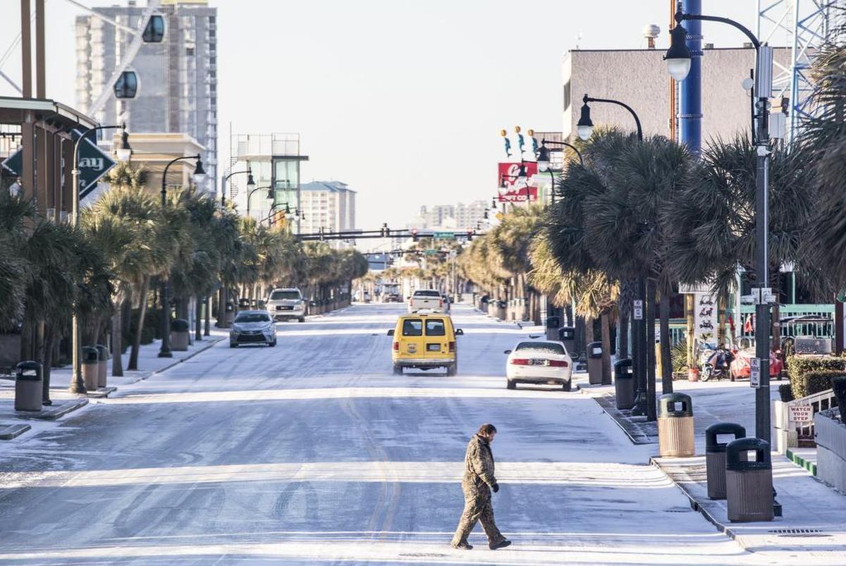 A pedestrian carefully crosses Ocean Boulevard in Myrtle Beach on Thursday morning. The Grand Strand missed out on the heaviest snows from Winter Storm Grayson, but area roads were solid sheets of ice on Thursday morning Thursday. Jan. 4, 2018.