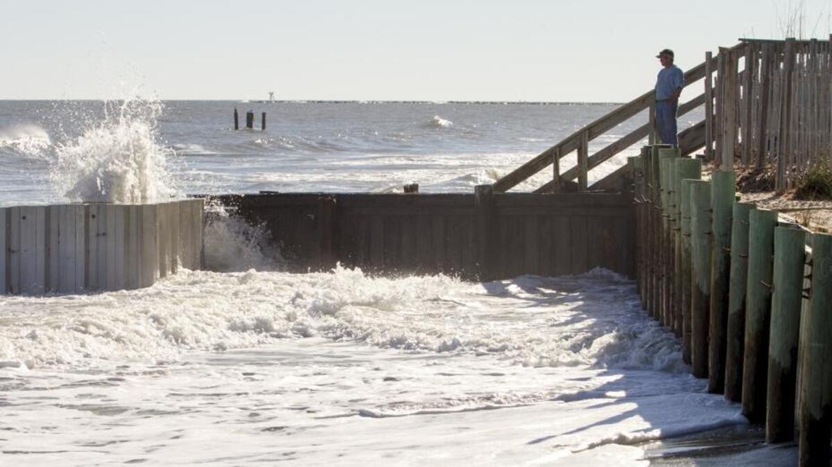 A man watches the waves crash against the groins and sea wall on the South end of Garden City Beach. Garden City Beach suffered severe beach erosion in this year's storms and floods but funding for beach renourishment may be years off.
