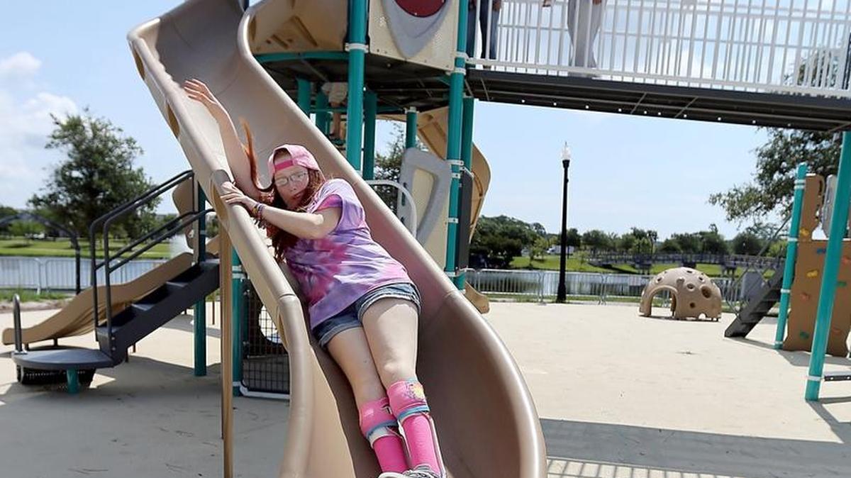 Myranda Mishler slides down at Savannah's Playground on Monday. Mishler, who wears braces on her legs and spends some days in a wheelchair, is visiting the area from Florence. The playground is expected to be open soon but a definite opening is set for Labor Day weekend. The playground is located beside Crabtree Gymnasium across the lake from The Market Common.