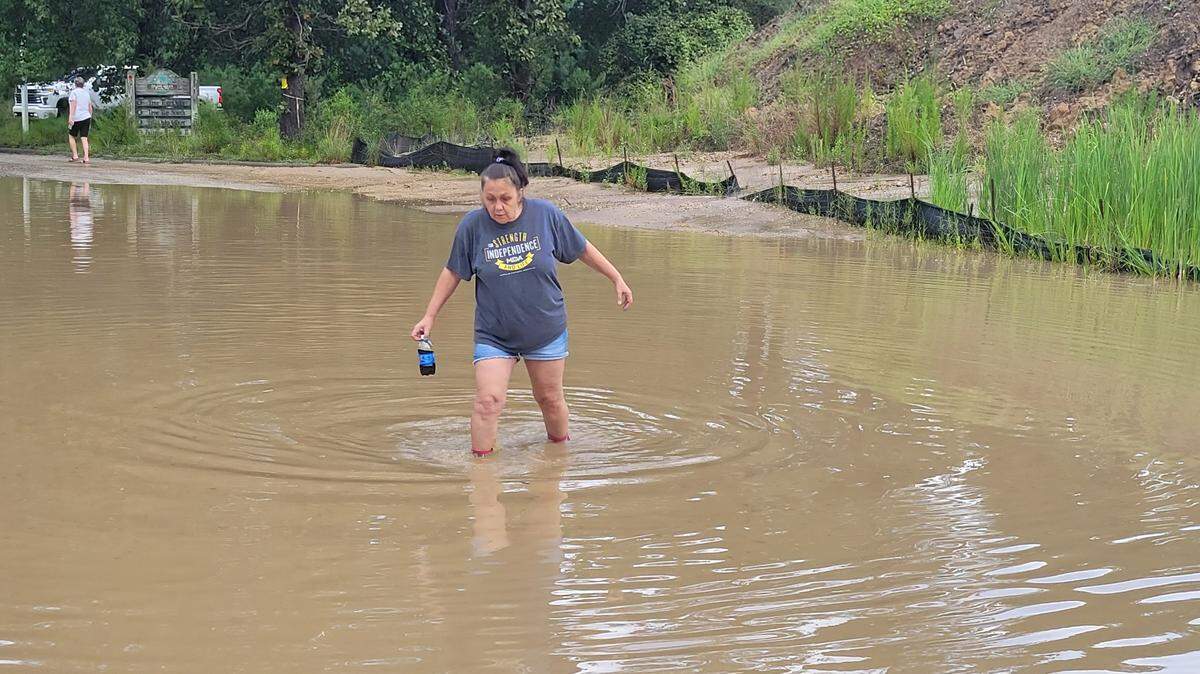Bernadette Sandlass navigates a flooded portion of road inside Horry County’s Island Green community following heavy rains on Friday Aug. 19, 2022.