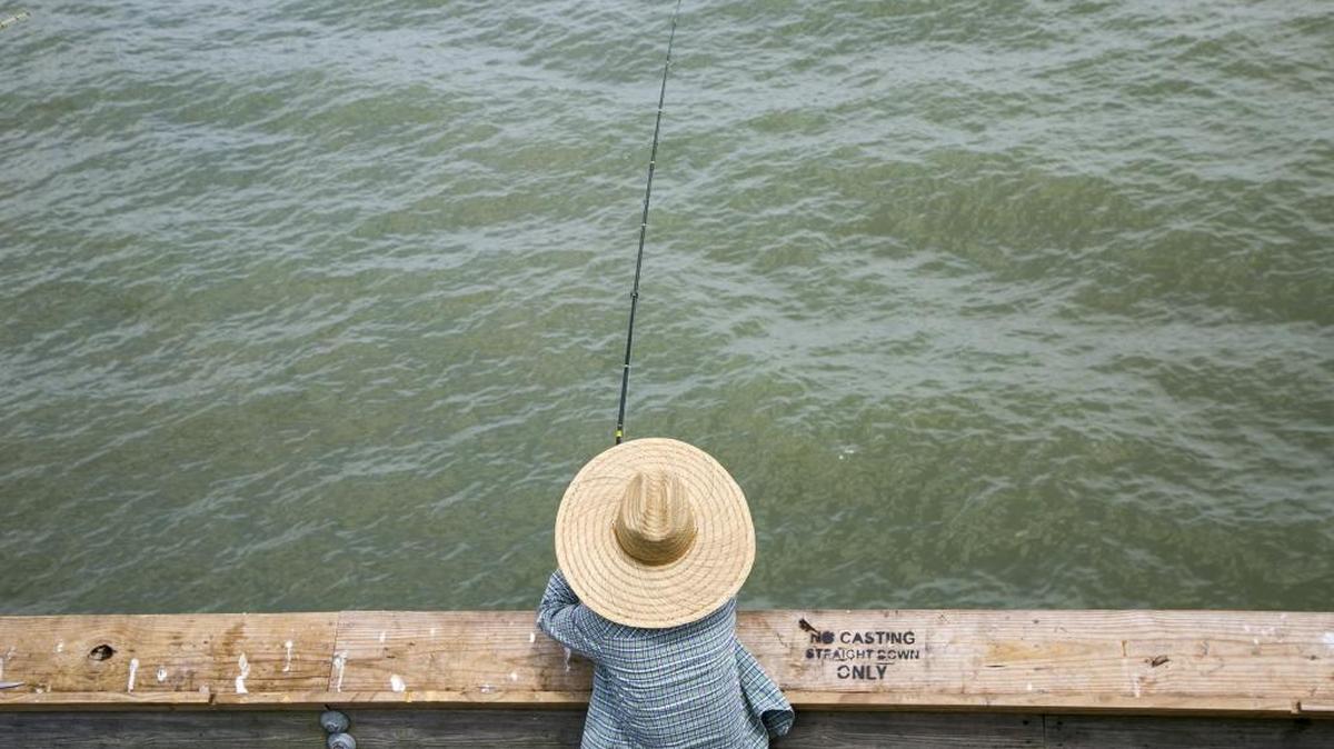 Sun Kim of Fayetteville, N.C. fishes under a big hat on the Apache Pier. Myrtle Beach and North Myrtle Beach already have laws on the books regarding beach fishing, and both cities allow beach patrols to regulate fishing during peak activity times.