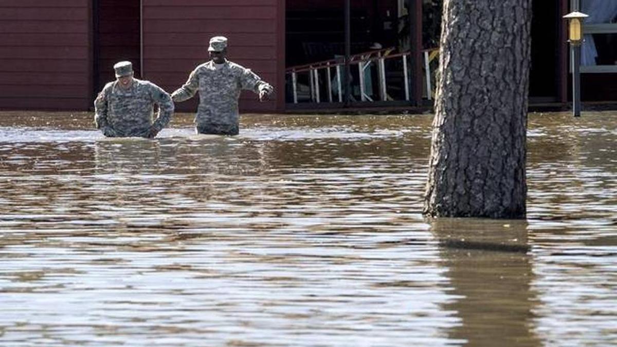 Sgt. Seth Morgan and Pfc. Adam Williams from the National Guard help each other wade through flood waters as they go door to door in Conway flood areas checking on residents.
