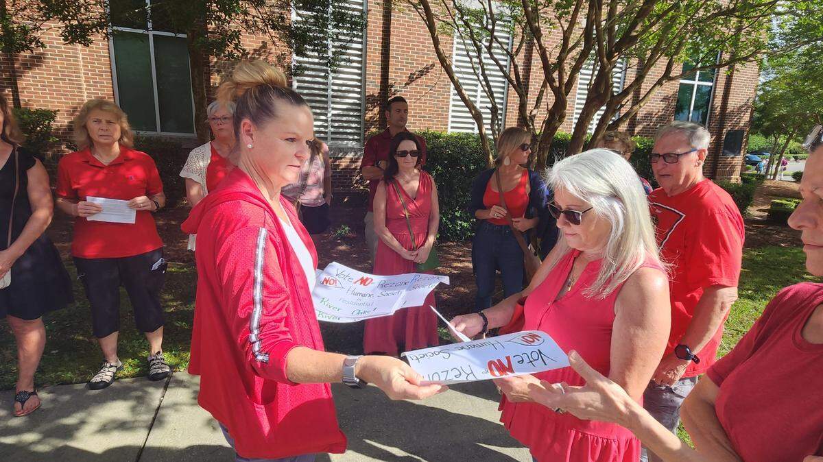 Robin Lutz hands out placards ahead of a June 20, 2023 Horry County Council meeting urging members to oppose a rezoning that would clear the way for a multi-million dollar Grand Strand Humane Society facility.