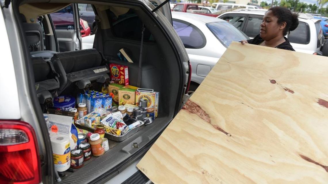 After loading the back of her vehicle with food Maria Minier loads a recently purchased wood panel to be used in preparation for Hurricane Irma, in Carolina, Puerto Rico, Tuesday, Sept. 5, 2017.
