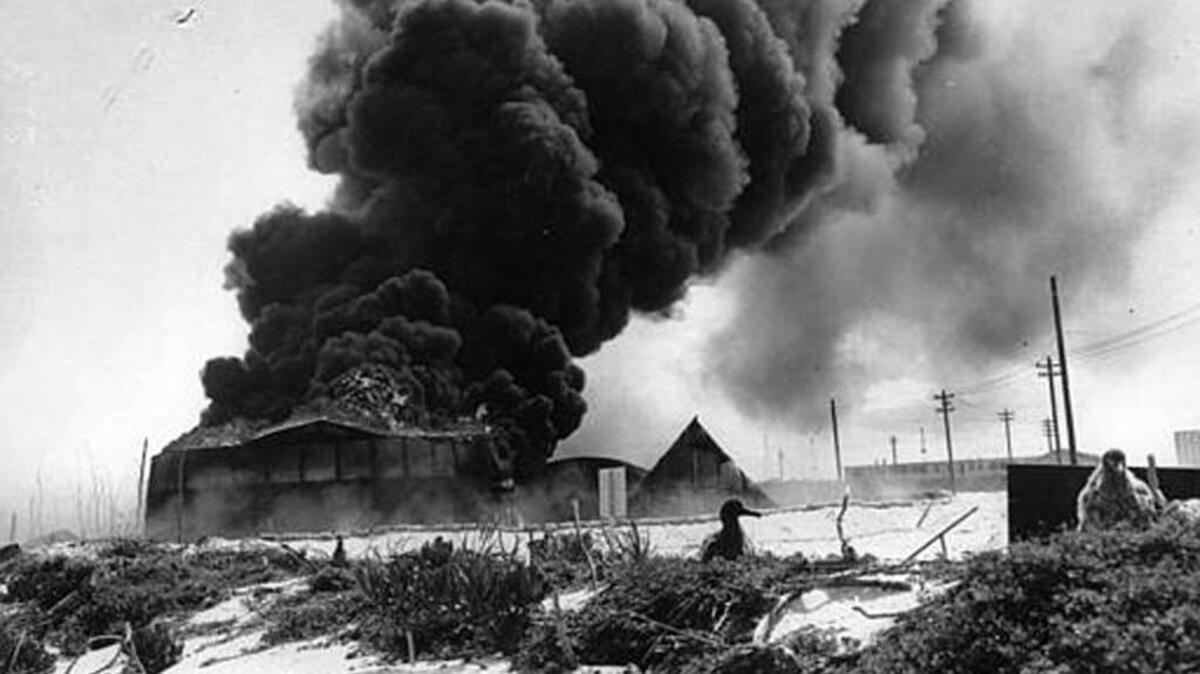 In this Sept. 8 1942 file photograph, black smoke rises from a burning U.S oil tank, set afire during a Japanese air raid on Midway Atoll.