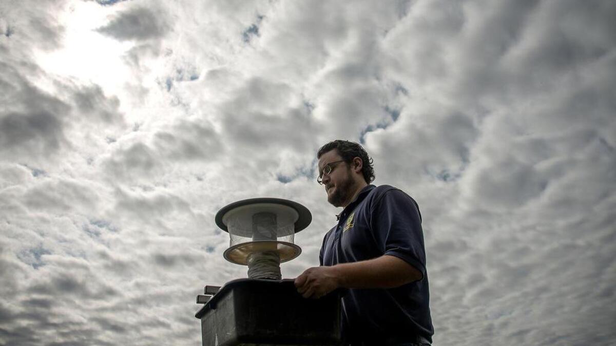 Microbiologist Spencer Lockwood carries a mosquito trap in Dallas. The trap is comprised of a tub for stink water, a small suction fan, a mosquito net and a small battery for powering the suction fan.