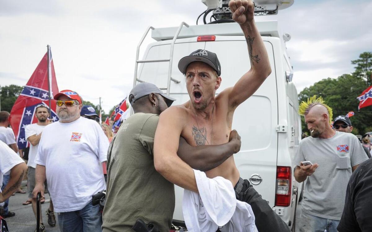 
Confederate flag supporter Jerry Gray of Conyers, Ga., is held back by a fellow supporter as he yells at Ku Klux Klan members to go home, while he and others protest what they believe is an attack on their Southern heritage during a rally at Stone Mountain Park in Stone Mountain, Ga., on Saturday, Aug. 1, 2015. 
