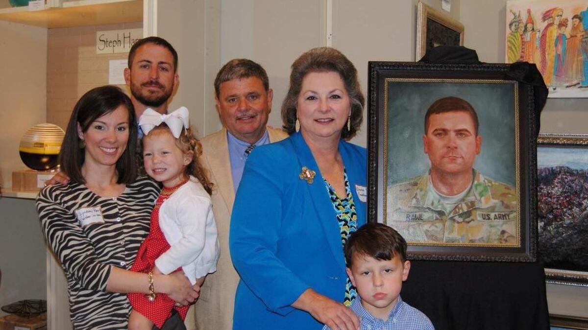 Diane Rawl (center), surrounded by family members, with a painting of her late son Ryan in 2014.