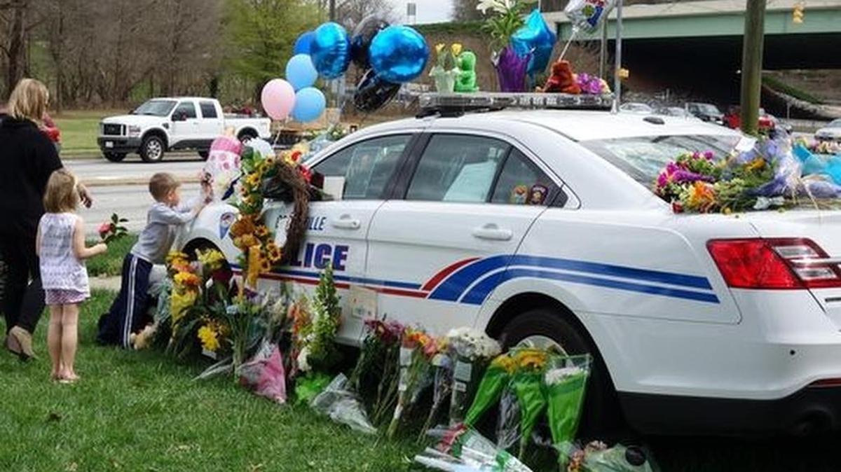 A young boy and his family leave flowers and a card in memory of Officer Allen Jacobs Saturday.(Photo: ANNA LEE/Staff)