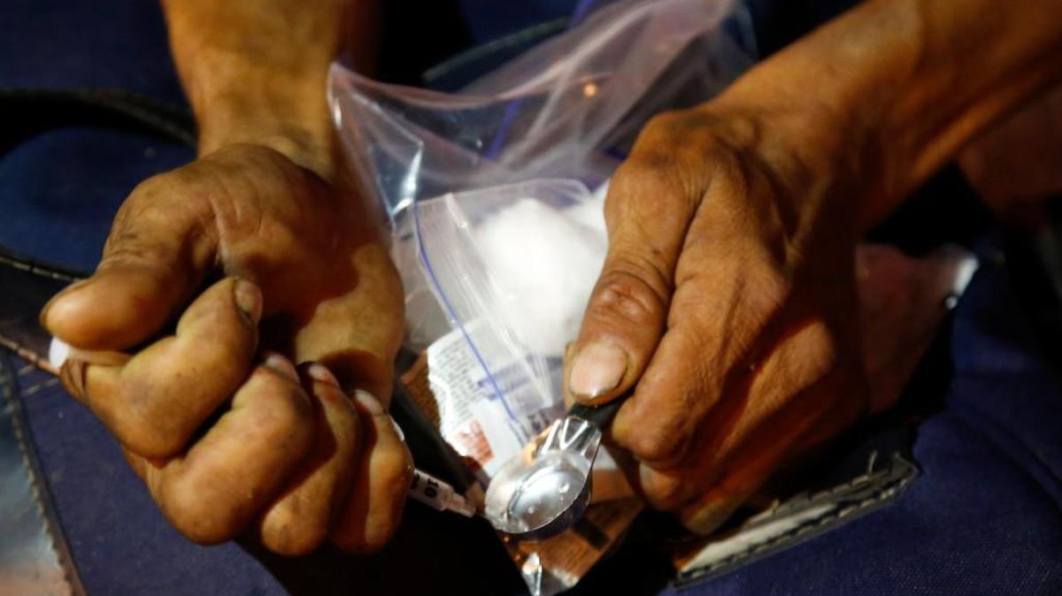 A drug addict prepares shoot up heroin after receiving a kit including a spoon, a rubber tube, cotton, sterilized water and clean syringes distributed by a program sponsored by the Open Society Foundation and government agencies in Dosquebradas, Colombia.