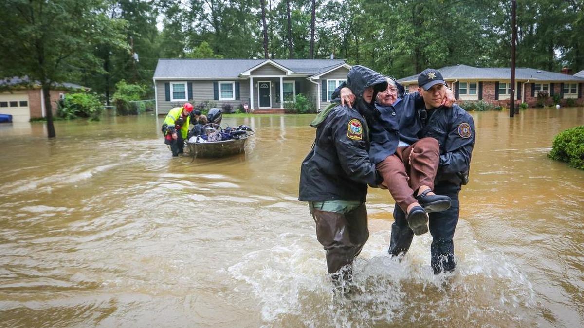 
DNR officer Brett Irvin and Lexington County Deputy Dan Rusinyak carry June Loch to dry land after she was rescued Monday from her home in the Pine Glen subdivision off of Tram Road in the St. Andrews area in northwest Columbia. 

