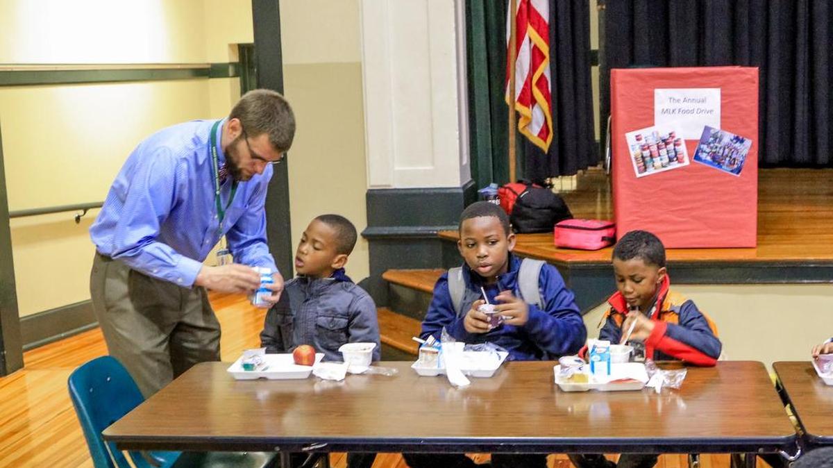 Logan Elementary principal Chris Richards helps his students who arrived before 7:30 a.m. as they have breakfast before starting their day. Students who arrive late to school might miss out on the free breakfast service.