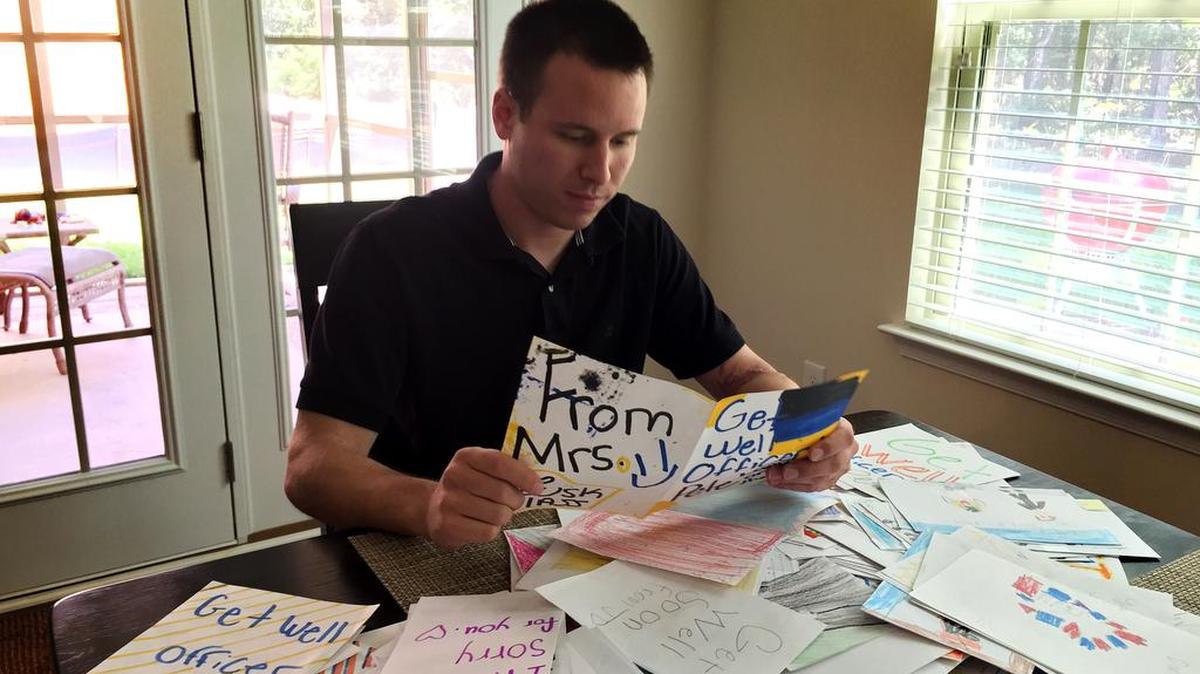 Officer Pete Conklin looks through get-well cards he received from Midlands school children after he was injured in May.