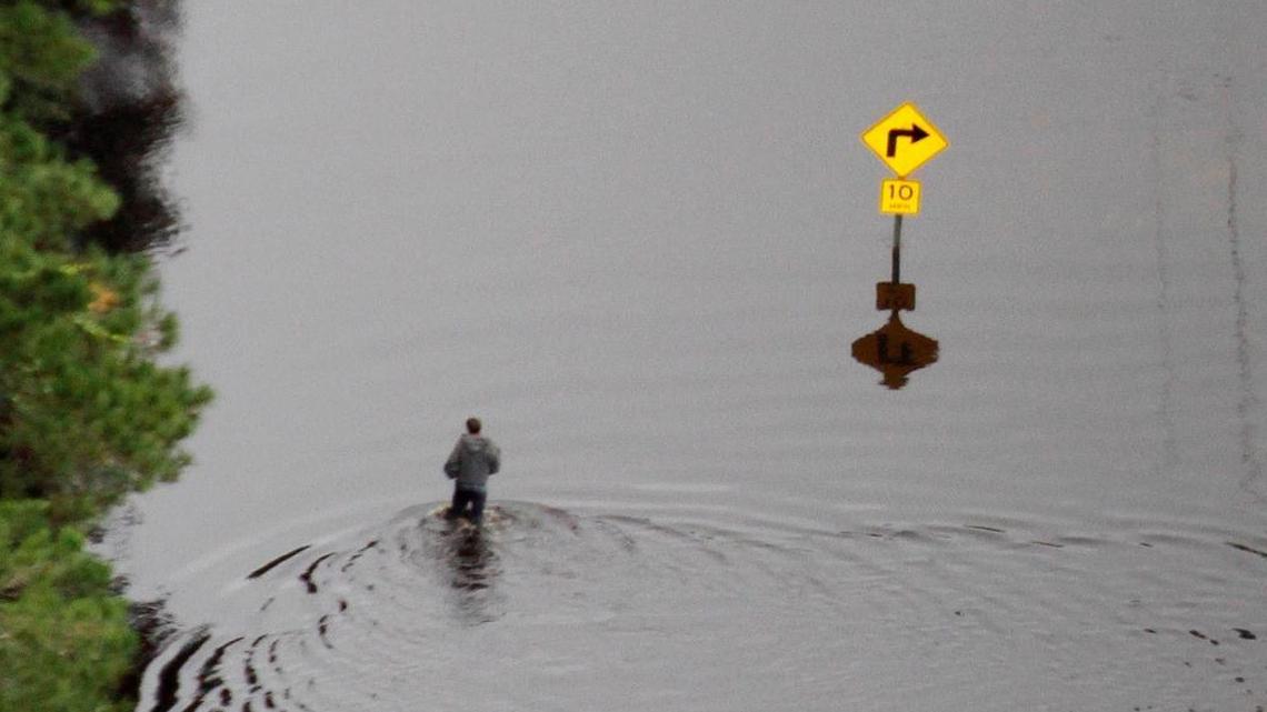 
A man walks on a flooded roadway near the Waccamaw River.
