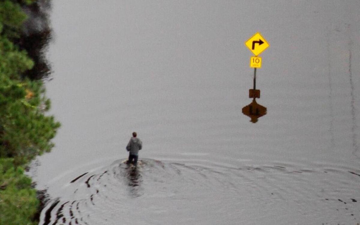 
A man walks on a flooded roadway near the Waccamaw River.
