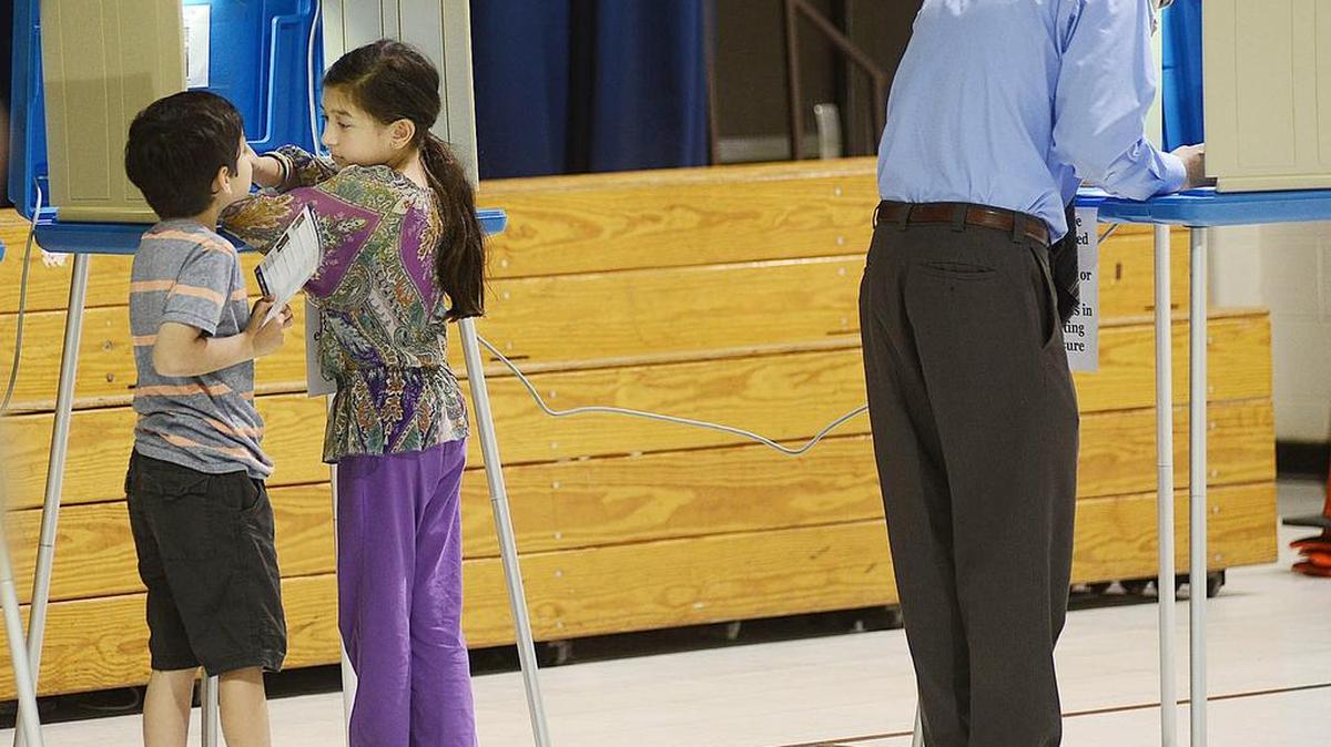 Geoff Coltrane, right, fills out his ballot at Southwest Elementary School in Durham, N.C., while his children Devak, 8, and Asha, 10, play in a voting booth.
