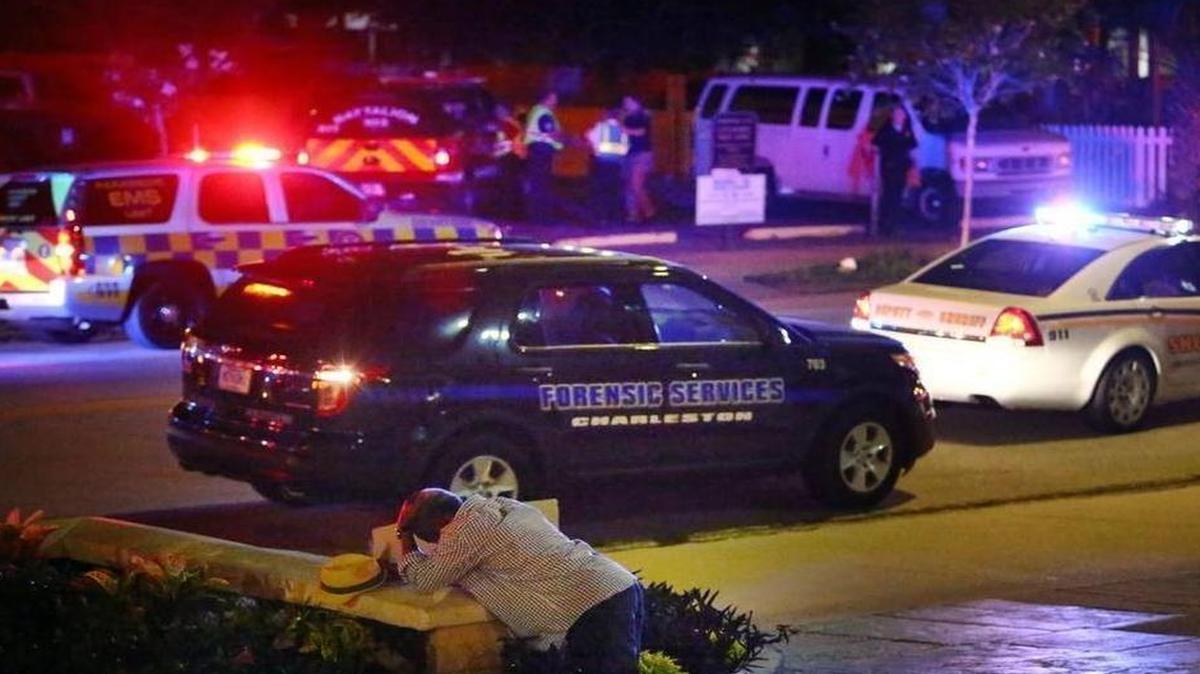
A man kneels across the street from where police gather outside the Emanuel AME Church following a shooting June 17, 2015, in Charleston, S.C. | Wade Spees AP
