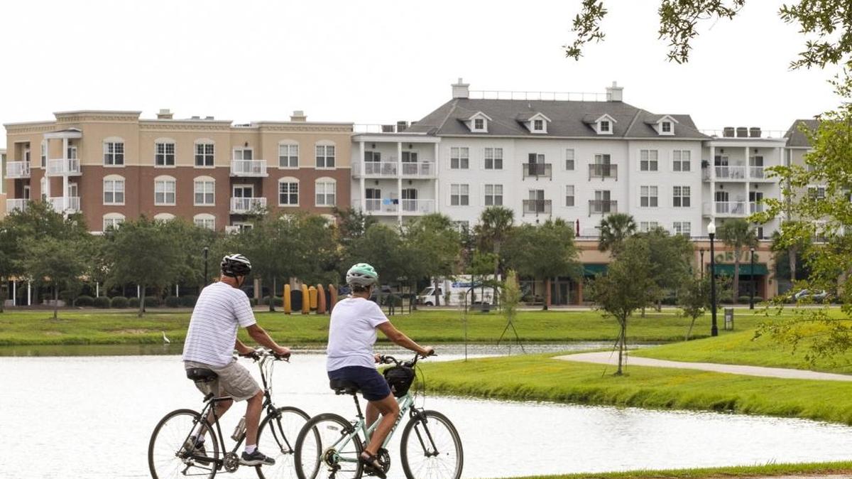 A couple rides bicycles around the lake at Grand Park at Market Common earlier this year.