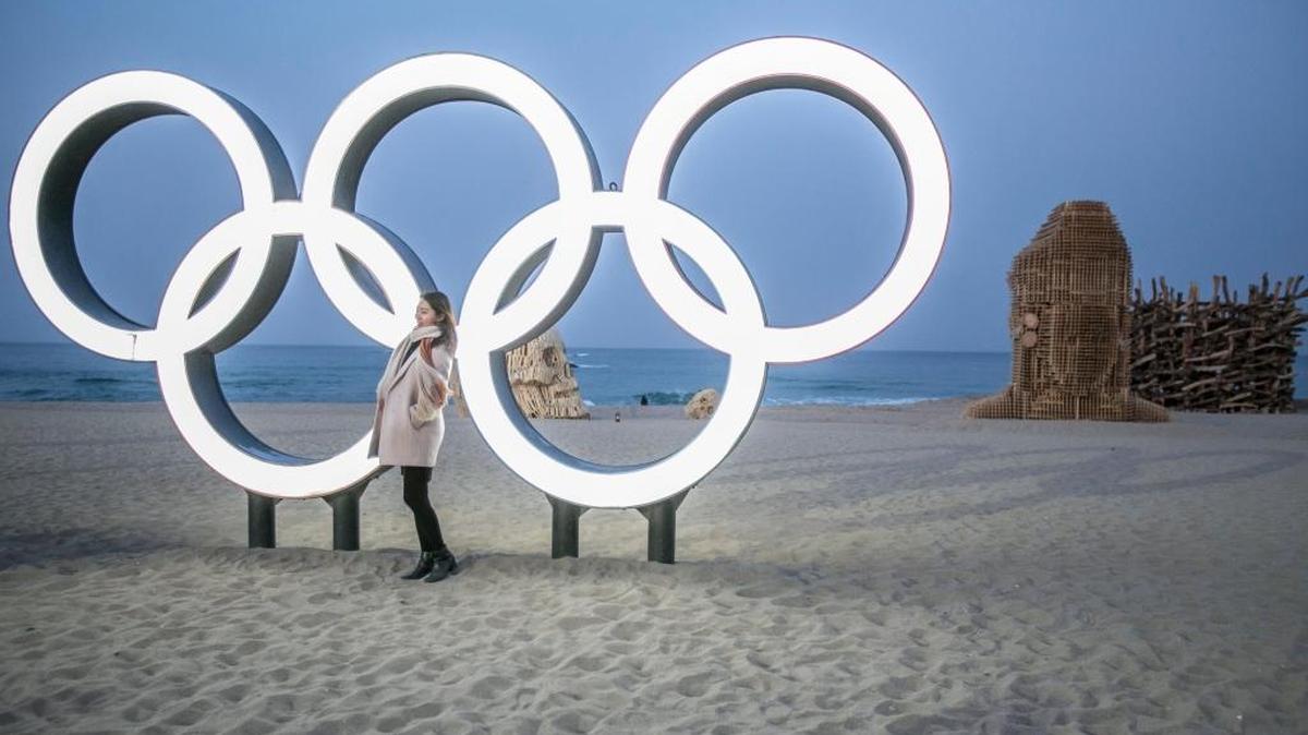 A South Korean woman poses for a photograph in front of an Olympic Rings sculpture on Gyeongpodae Beach ahead of the 2018 Pyeongchang Winter Olympic Games in Gangneung, South Korea.