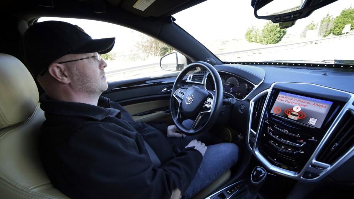 FILE - This Friday, Nov. 13, 2015 file photo provided by Virginia Tech shows Virginia Tech Center for Technology Development Program Administration Specialist Greg Brown behind the wheel of a driverless car during a test ride showing the alert system handing over automation to the driver, while traveling a street in Blacksburg, Va.