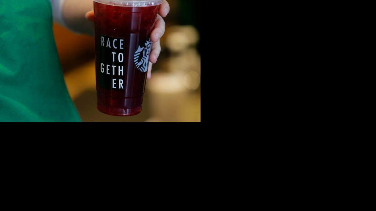 
A Starbucks barista holds an iced tea drink with a “Race Together” sticker on it March 18 at a Starbucks store in Seattle. Starbucks’ effort to spark a dialogue on race caused an outcry from customers on social media and elsewhere. 
