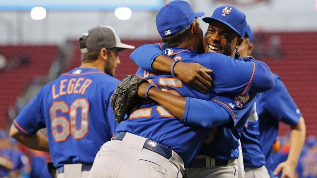 
New York Mets right fielder Curtis Granderson (right) hugs bullpen coach Ricky Bones (25) after clinching the NL East title following their 10-2 win over the Cincinnati Reds.
