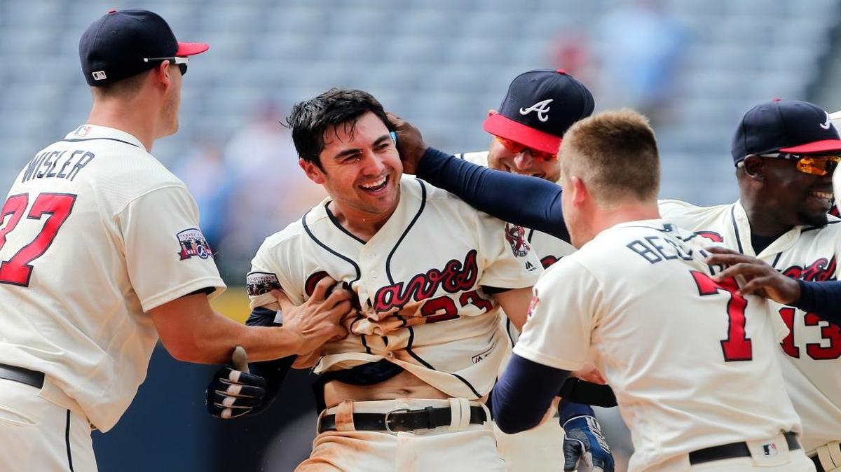 Atlanta’s Chase d’Arnaud (center) is mobbed by teammates after driving in the winning run with a base hit in the ninth inning against Colorado on Sunday.