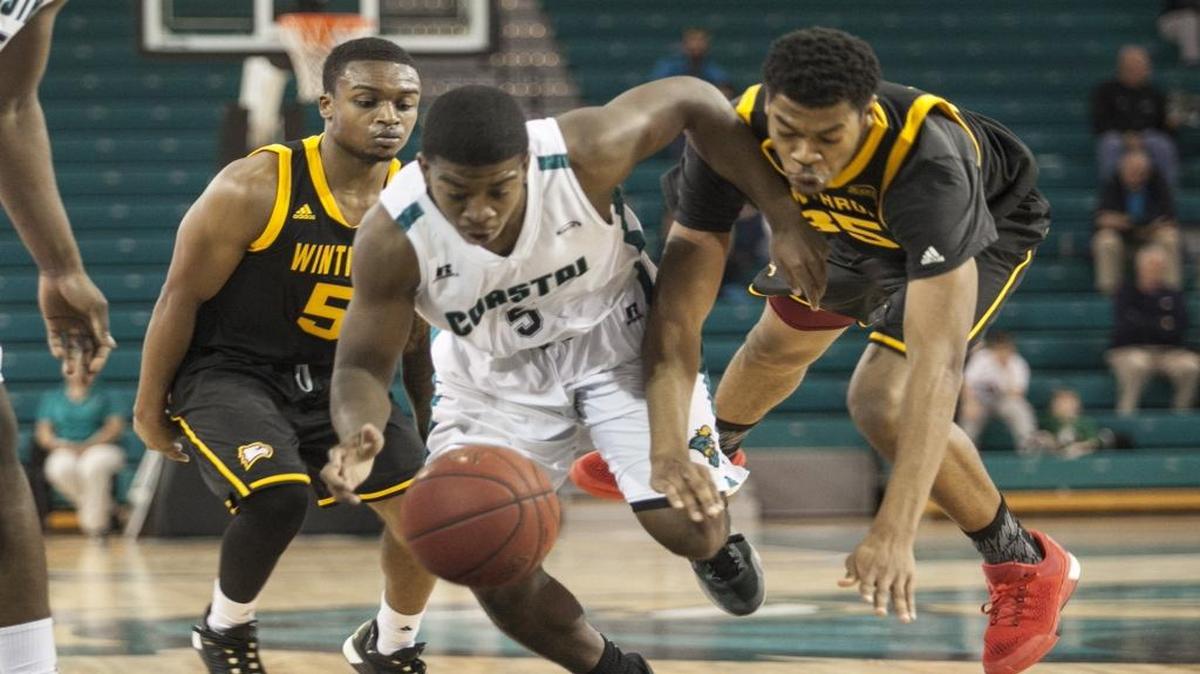 Coastal Carolina’s Jaylen Shaw (front) battles Winthrop’s Jared Scott (right) for a loose ball during the teams’ meeting in January.