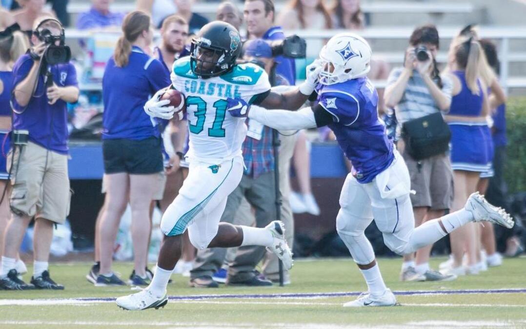 Coastal Carolina’s De’Angelo Henderson (left) runs the ball against Furman on Saturday.