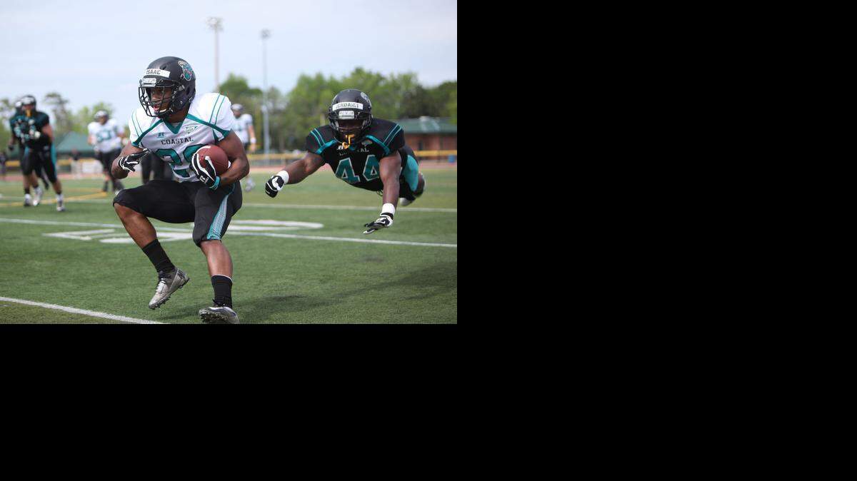 
Isaac Martin (left) dodges a diving tackle attempt by Jordhan Brown during Coastal Carolina’s spring game Saturday at Doug Shaw Memorial Stadium.
