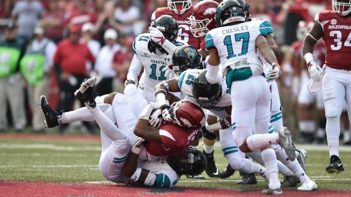 The Coastal Carolina defense, led by linebackers Shane Johnson (bottom) and Laqavious Paul (25) tackle an Arkansas ball carrier Saturday.
