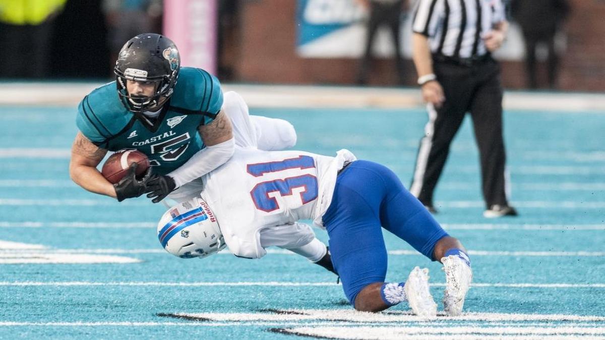 
Coastal Carolina’s A.J. Sattinger is knocked off his feet by Presbyterian’s Steve Osondu after a pass reception. 
