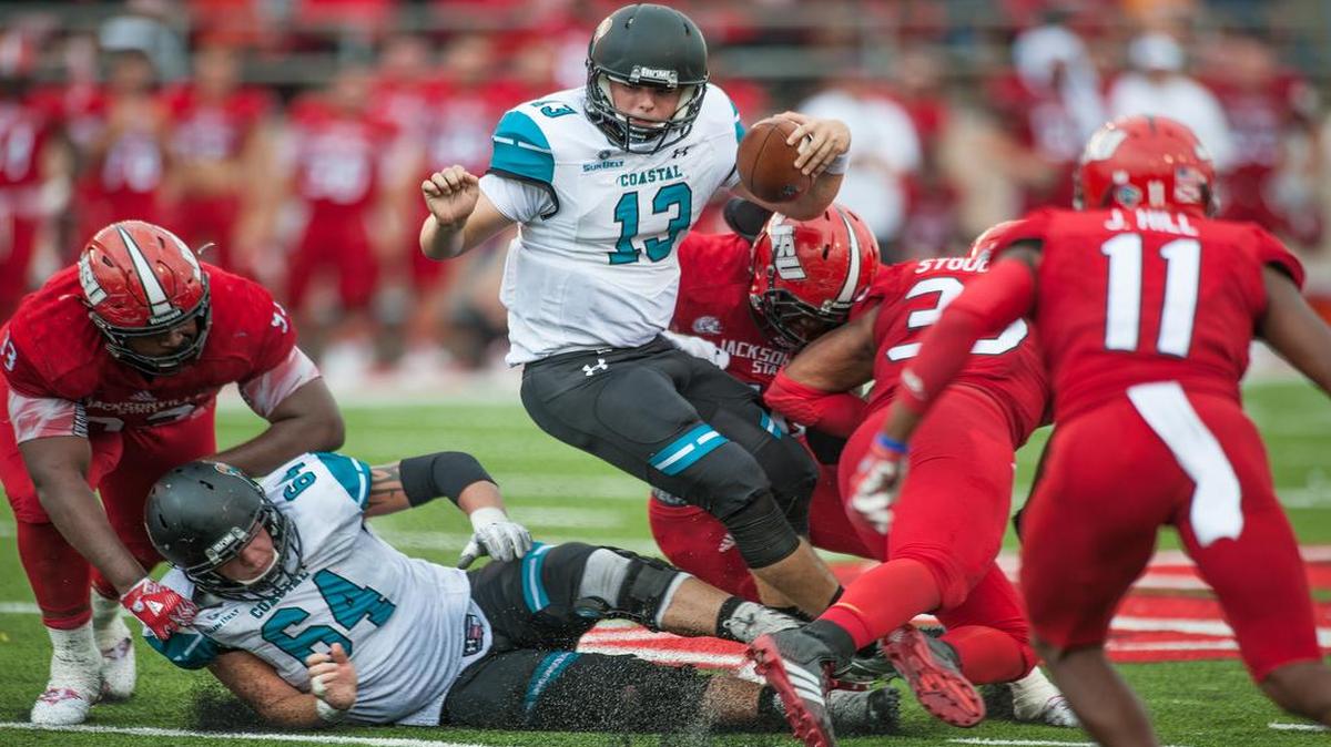 Coastal Carolina quarterback Tyler Keane (13) runs as Jacksonville State defenders swarm during Saturday’s game.