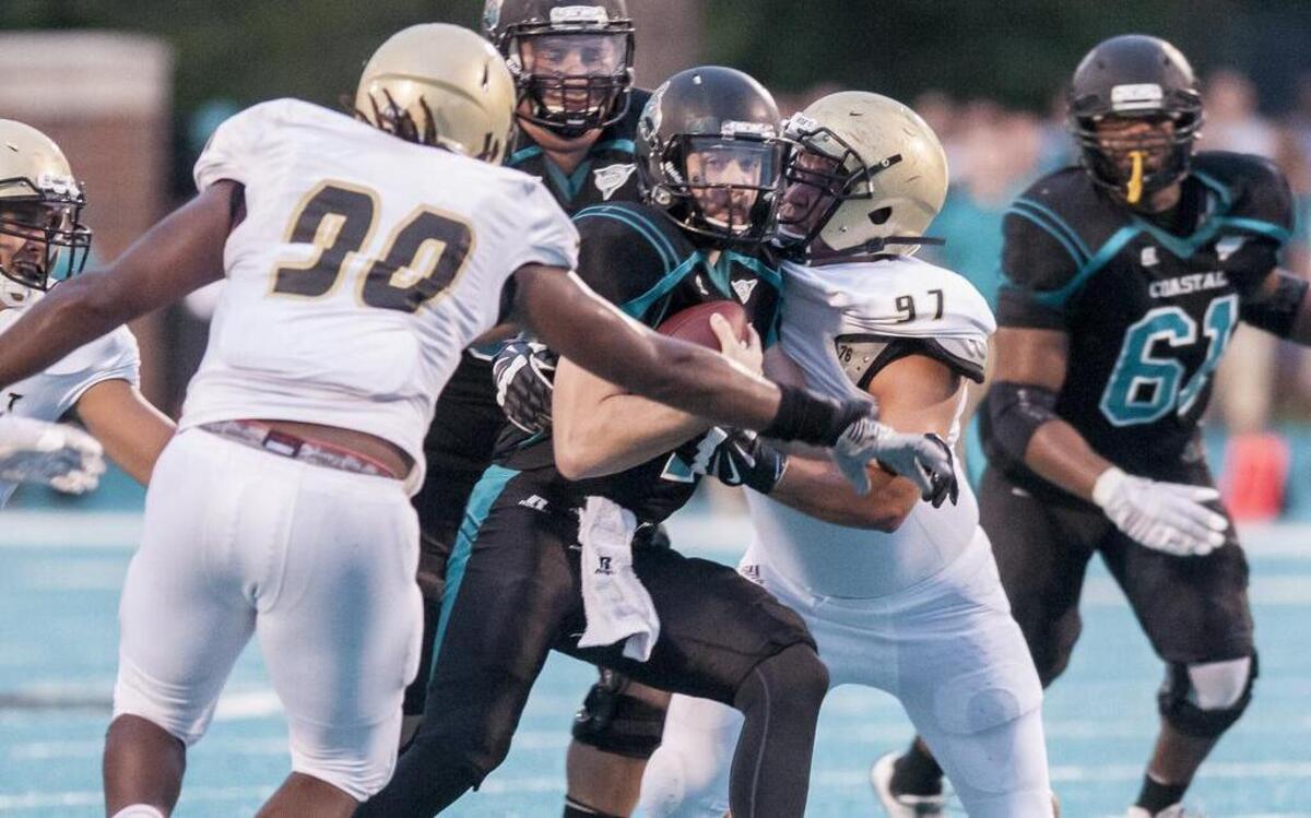 
Coastal Carolina quarterback Alex Ross (center) runs the ball while under pressure from Bryant defenders Saturday. 
