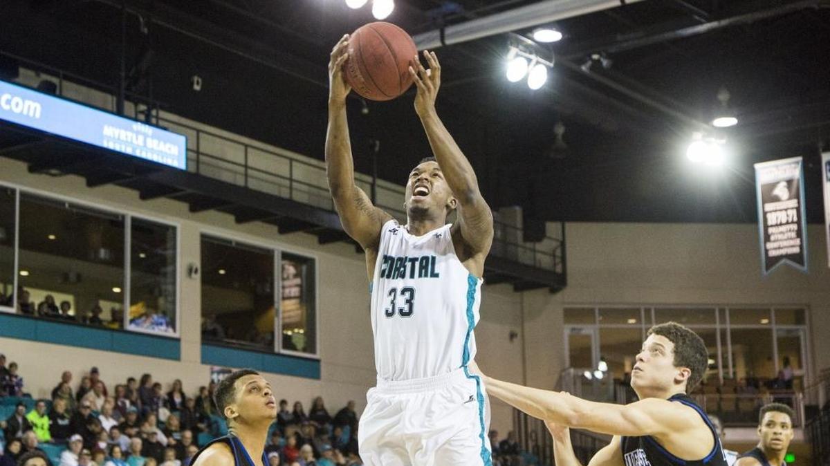 Coastal Carolina’s Ron Trapps rises high to get a shot over Presbyterian College defenders Thursday during the game between Big South Conference foes.