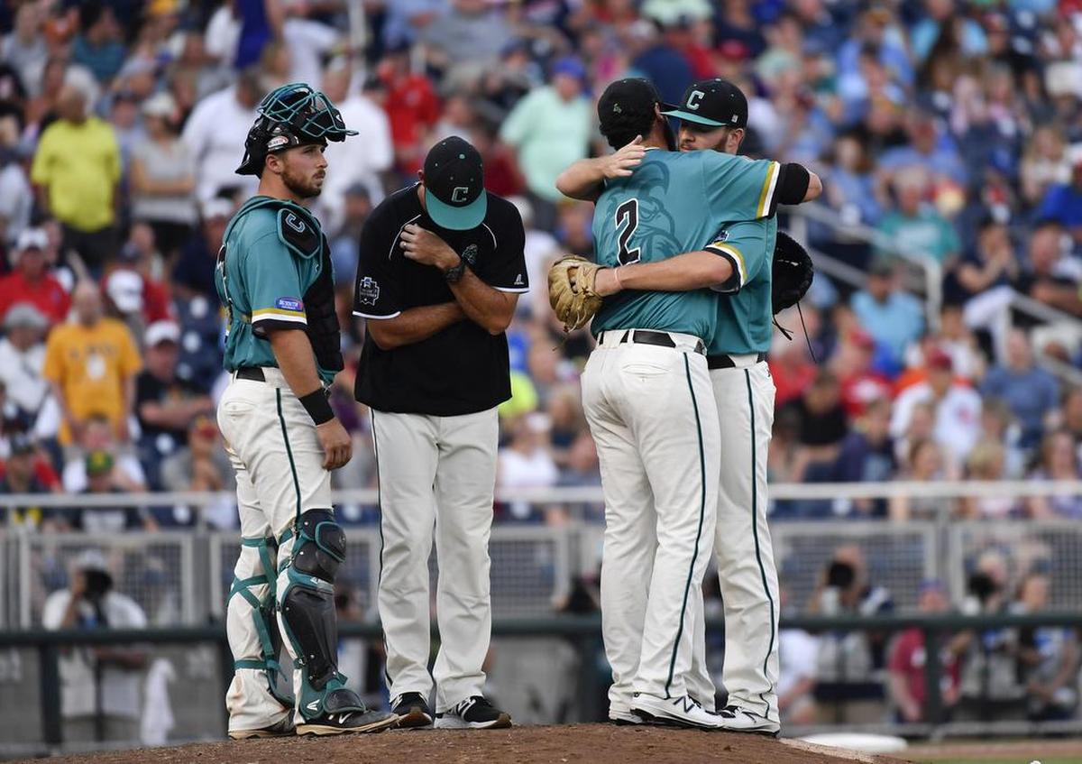 Coastal Carolina pitcher Zack Hopeck (2) is hugged by relief pitcher Cole Schaefer during a pitching change as catcher David Parrett (12) and pitching coach Drew Thomas wait against Arizona in the seventh inning in Game 1 of the NCAA Men’s College World Series finals baseball game in Omaha, Neb., Monday, June 27, 2016.
