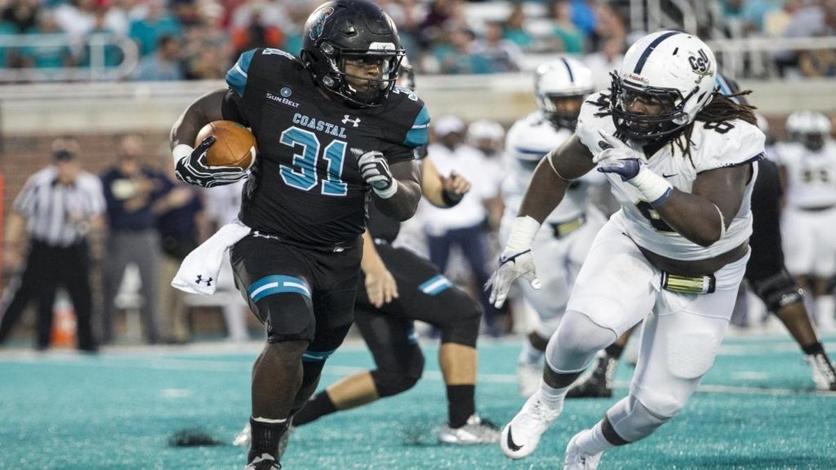 Coastal Carolina’s De'Angelo Henderson runs past Charleston Southern’s Anthony Ellis on Oct. 1.