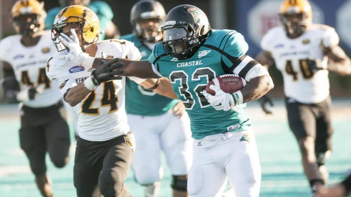 Coastal Carolina running back Osharmar Abercrombie stiff arms Kennesaw State's Marcus Thurman on his way to a big gainer last Saturday.