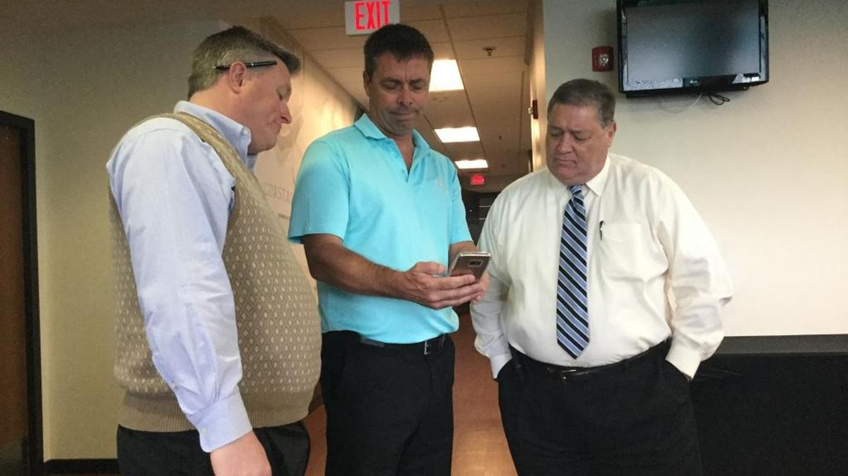 Coastal Carolina athletic director Matt Hogue (left) and school president David DeCenzo (right) look on as Chanticleers men's soccer coach Shaun Docking searches his phone for the fate of his team in the NCAA Division I Men’s Soccer Tournament during the watch party on campus Monday. Coastal Carolina will host former Big South rival Redford in the first round Thursday.