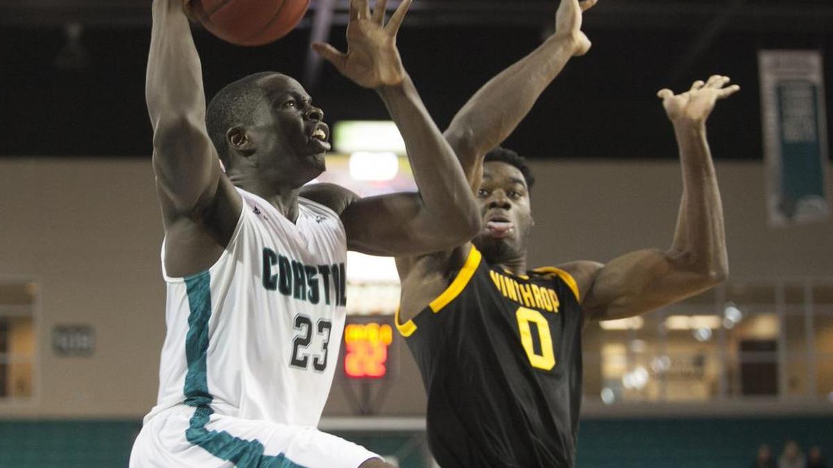 Coastal Carolina’s Badou Diagne goes strong to the hoop against Winthrop's Duby Okeke during Saturday’s match-up at The HTC Center. The Chants beat Winthrop 82-63, earning head coach Cliff Ellis his 700th win at the Division I level.