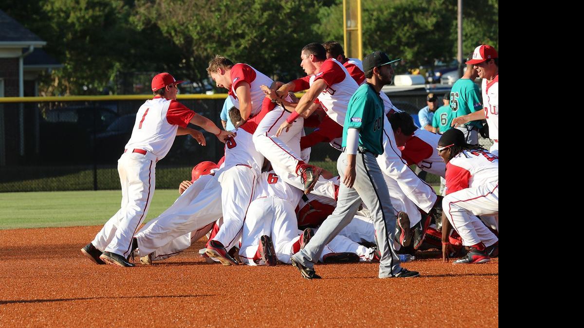 Radford players celebrate in a dogpile as Coastal Carolina players walk off the field following the Highlanders win in the Big South championship game.
