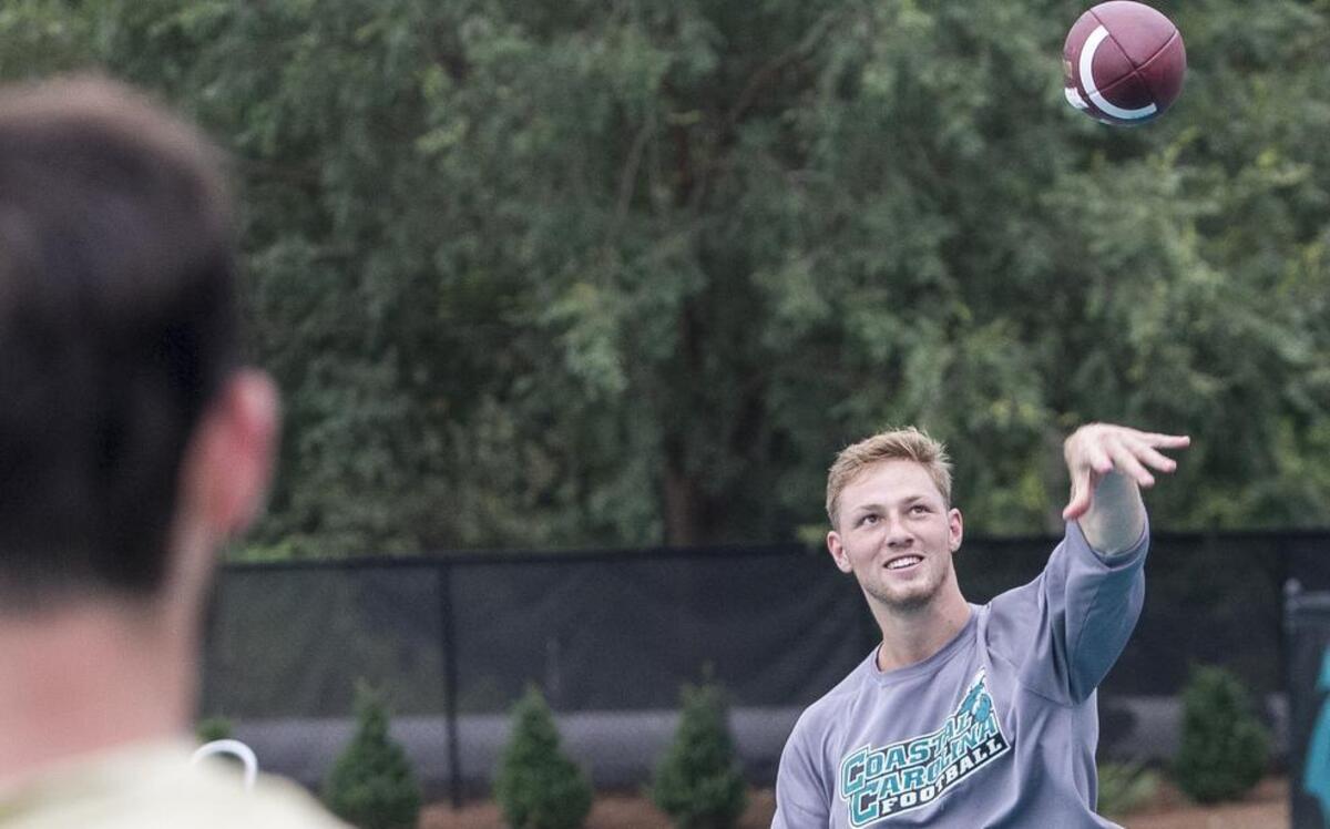 
Coastal Carolina’s Richie Sampson tosses the ball with quarterback Alex Ross on the sidelines during the team’s first practice Monday.
